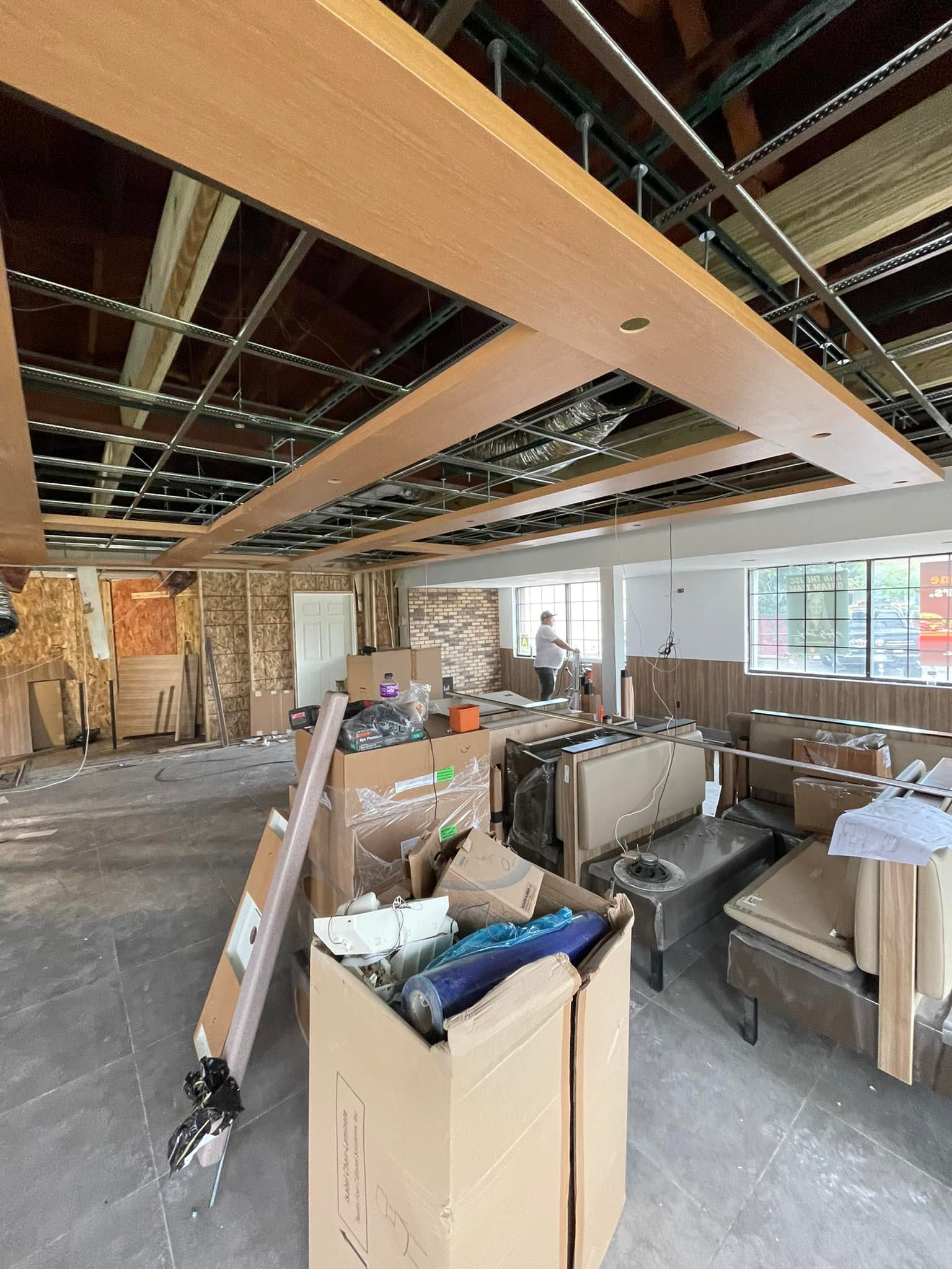 Restaurant interior under renovation with new ceiling installation, booth seating, and construction materials on site